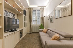 A living room with a television, sofa, and artwork on the walls.