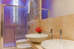 A bathroom with two sinks, a shower, and a mirror.