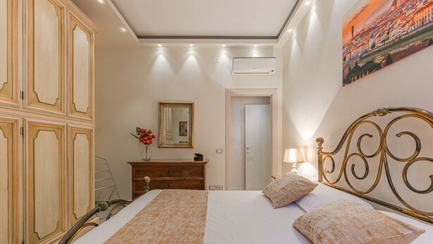 Une chambre à coucher avec un lit, une commode, un miroir et une porte.
