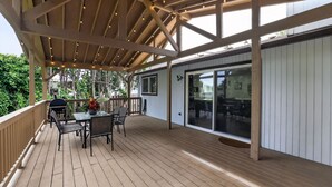 A wooden deck with a covered area, outdoor furniture, and a glass door leading to an interior space. - Family Fairview Home | Gorge Access & Covered Deck (Fairview)