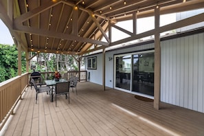 A wooden deck with a covered area, outdoor furniture, and a glass door leading to an interior space. - Family Fairview Home | Gorge Access & Covered Deck (Fairview)