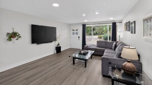 A modern living room with a flat-screen TV, a glass coffee table, a sofa, and a lamp. - Family Fairview Home | Gorge Access & Covered Deck (Fairview)