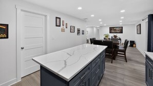 A modern kitchen with a marble countertop, dark cabinets, and a dining area with a table and chairs. - Family Fairview Home | Gorge Access & Covered Deck (Fairview)