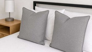 Ein Bett mit zwei Kissen, einer Nachttischlampe und einem Holznachttisch.