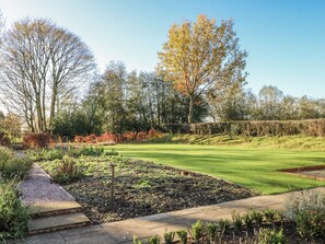 Ein gepflegter Garten mit Rasen, einem Kiesweg und vielfältigen Pflanzen.
