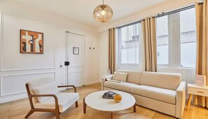 Ein Wohnzimmer mit Sofa, Sessel, Couchtisch und einer Pendelleuchte.