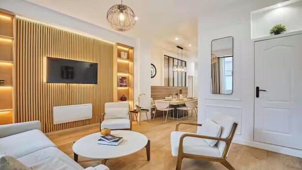 A modern living room with a flat-screen TV, a dining area, and a white door. - AN UNBEATABLE LOCATION IN THE HEART OF ONE OF PARIS'S MOST VIBRANT DISTRICTS (Paris)