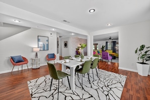 A modern dining area with a white table, green chairs, and a patterned rug. - NEW! Southern Comfort Escapes 5BR for 14 Near NASA (Madison)