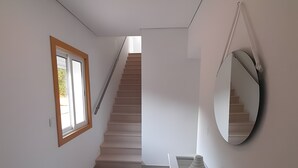 A modern interior with a staircase, a window, and a mirror. - Garden Hill R – Spacious Patio, Pool, Parking, Old Town (Albufeira)