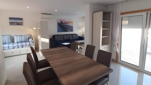 A modern living room with a dining table, sofa, and artwork on the walls. - Garden Hill R – Spacious Patio, Pool, Parking, Old Town (Albufeira)