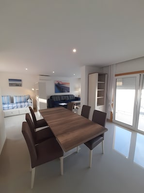 A modern living room with a dining table, sofa, and artwork on the walls. - Garden Hill R – Spacious Patio, Pool, Parking, Old Town (Albufeira)