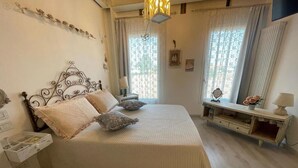 A bedroom with a bed, bedside tables, a nightstand, a dresser, and a window with curtains. - Tenuta Borgato Morelli (Este)