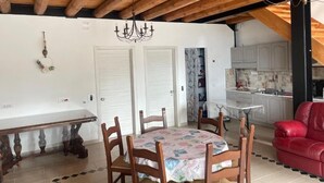A dining area with a round table and chairs, a chandelier, and a red sofa. - Tenuta Borgato Morelli (Este)