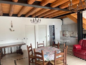 Un coin repas avec une table ronde et des chaises, un lustre et un canapé rouge.