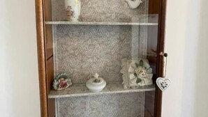 A wooden display cabinet with three shelves, each containing various decorative items. - Tenuta Borgato Morelli (Este)