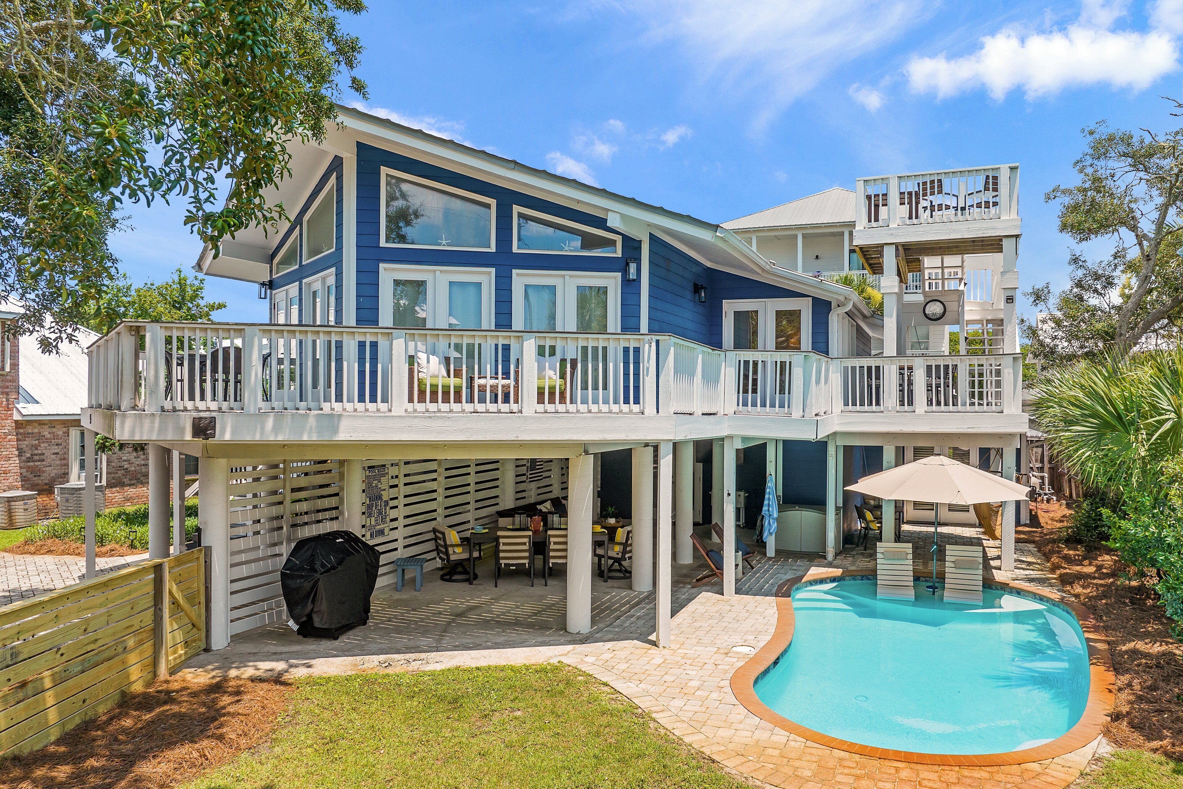 A two-story house with a balcony, a pool, and outdoor furniture.