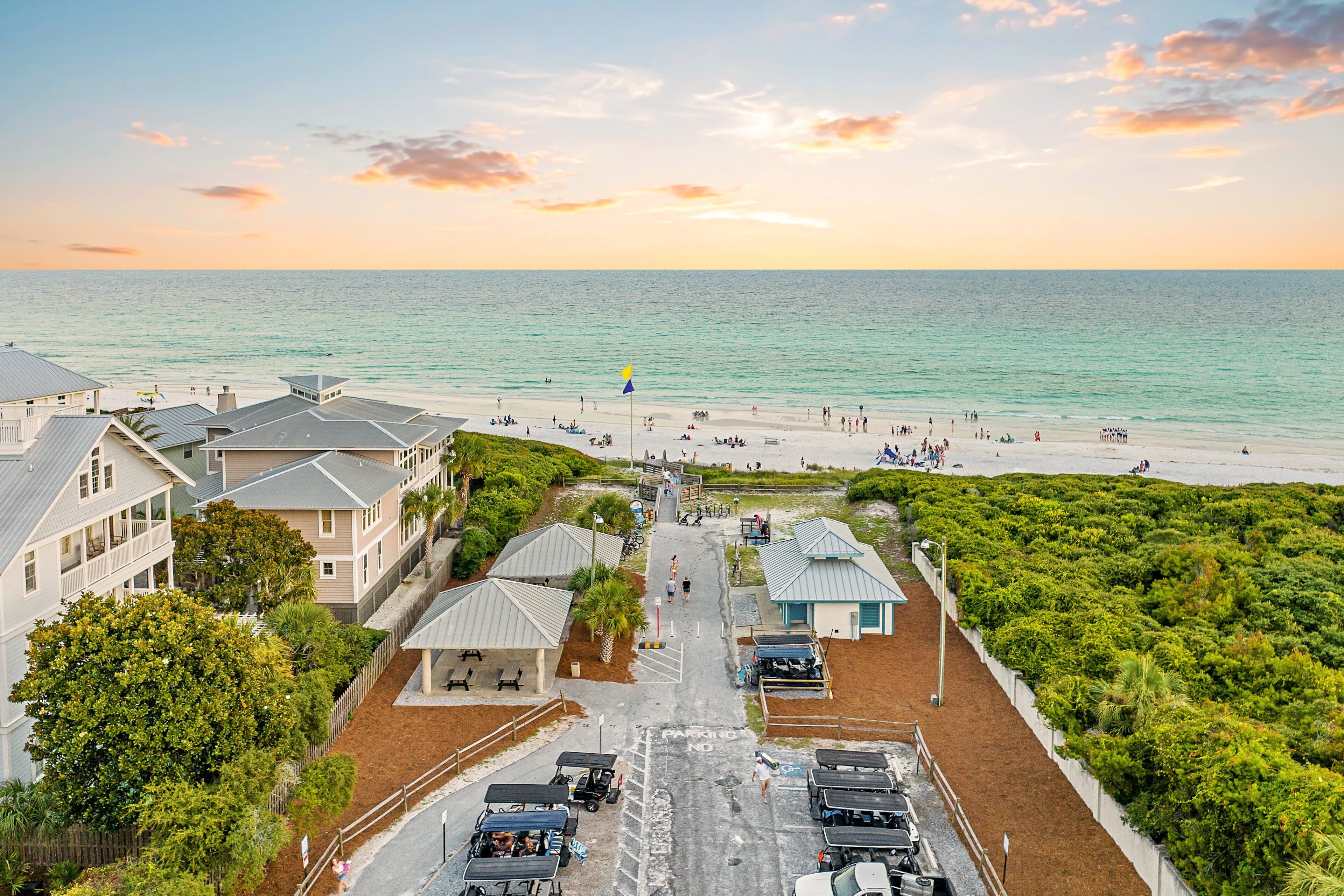 A coastal hotel with a beach view, parking area, and a flagpole.