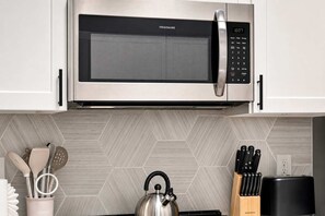 A kitchen with a stainless steel microwave, a kettle, and a knife block. - Boulevard Stays Quiet Modern 1BR with Pickleball, Pool, Parking & Gym (Chandler)