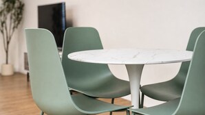Een eethoek met een ronde tafel en vier groene stoelen.