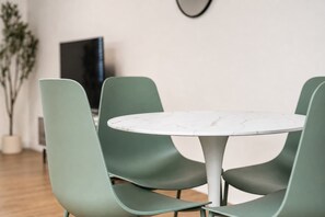A dining area with a round table and four green chairs. - Boulevard Stays Quiet Modern 1BR with Pickleball, Pool, Parking & Gym (Chandler)