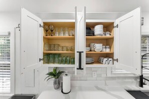 A kitchen with open cabinets displaying glassware, plates, and bowls. - Spacious Modern Home Minutes from ATL Airport (Atlanta)