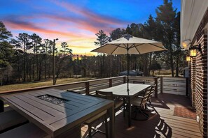 Une terrasse extérieure avec une table et des chaises, un barbecue et une vue sur une zone boisée.