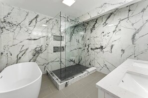 Une salle de bain moderne avec une douche à parois de verre, une baignoire sur pieds et un lavabo blanc.