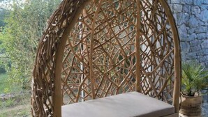 A wicker chair with a cushion, set on a stone floor, in a room with a stone wall and a window overlooking greenery. - 130m2 ground floor villa with private pool on 4000m2 of land (Les Arcs)