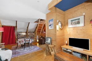 A cozy room with a wooden interior, a television, a desk with a computer, and a red curtain.
