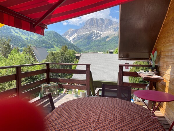 Un balcon avec une table Ă motifs, des chaises et une vue sur les montagnes.