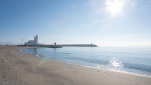 A coastal scene with a lighthouse, calm sea, and clear sky.