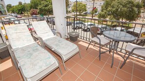 Ein Balkon mit zwei Lounge-Sesseln, einem kleinen Tisch und einem Stuhl.