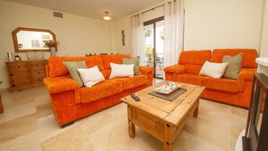 Ein Wohnzimmer mit zwei orangefarbenen Sofas, einem Holztisch und einer Kommode mit Schubladen.