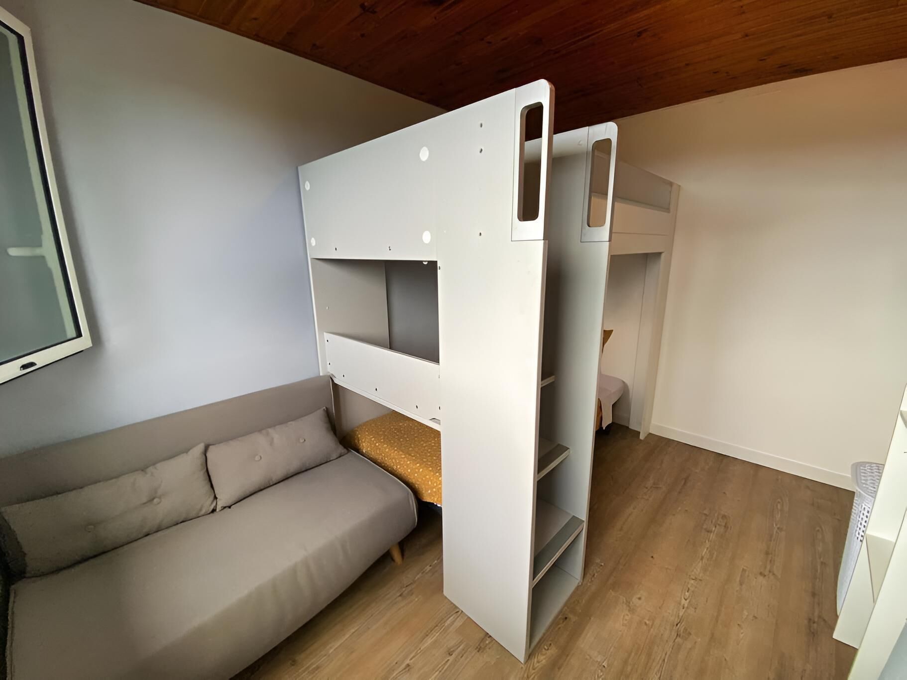 A room with a bunk bed, a sofa, and a television.