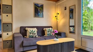 A modern living room with a sofa, a coffee table, a floor lamp, and a large window with a view of greenery.