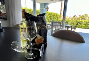 Une table avec une bouteille de vin, un verre à vin et un sachet de collations.