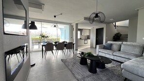 Una sala de estar moderna con un sofá gris, una mesa de centro y un comedor con sillas y una mesa.