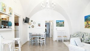 Um quarto espaçoso com área de jantar, sofá e lustre.