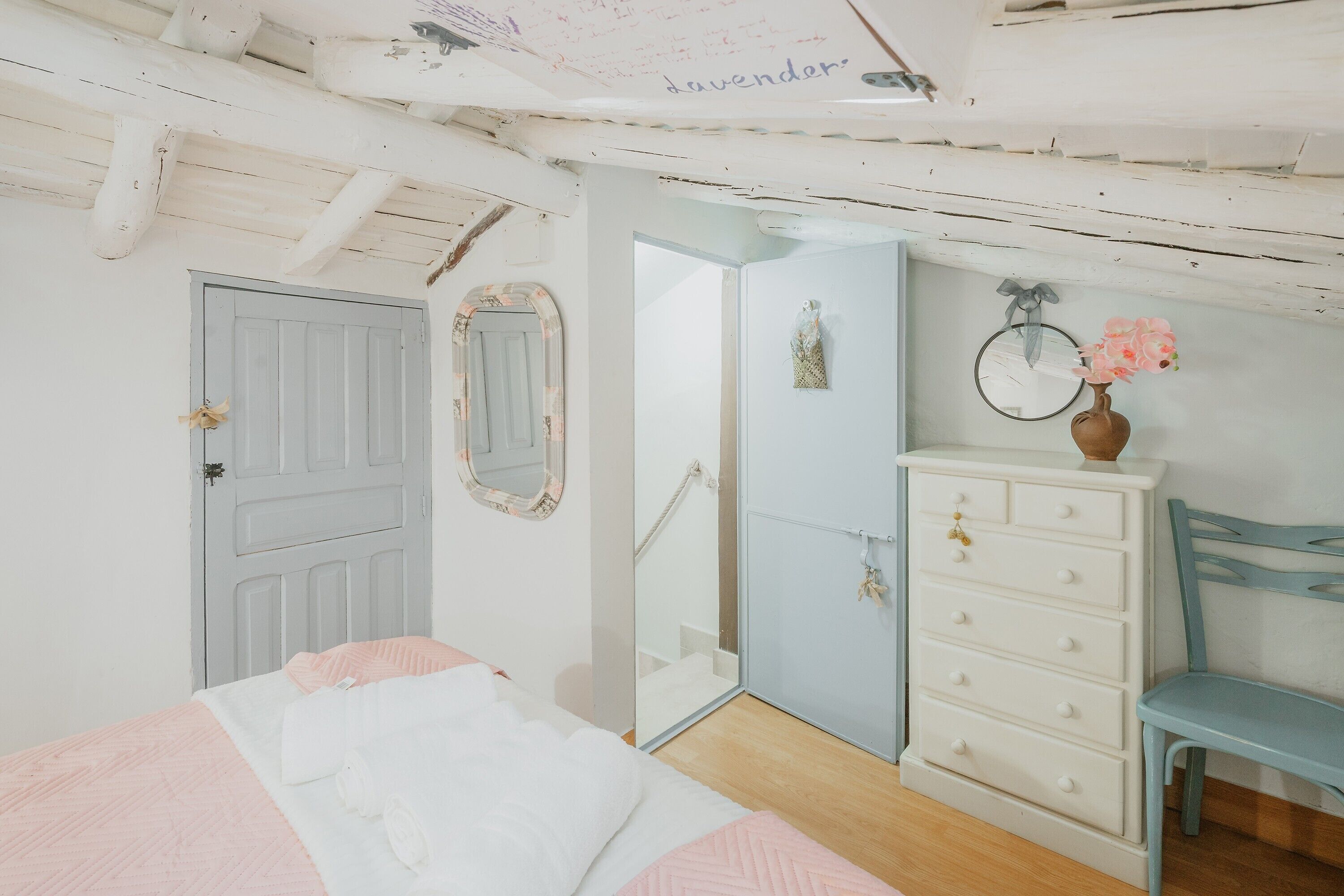 A bedroom with a bed, dresser, chair, and a door.