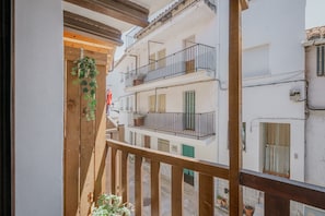 Een balkon met houten hekwerk, plantenbakken en uitzicht op omliggende gebouwen.