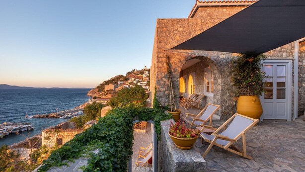 A stone building with a terrace overlooking the sea, featuring a large potted plant and wooden lounge chairs. - Beachfront Villa Ondyrelis, Divine Sea Views, Furnished Terrace, Hydra (Hydra)