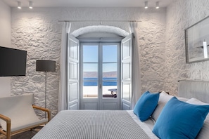 A bedroom with a bed, a chair, a TV, and a view of the sea through an open door. - Beachfront Villa Ondyrelis, Divine Sea Views, Furnished Terrace, Hydra (Hydra)
