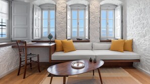 A room with a white stone wall, a wooden desk, a white sofa with yellow cushions, and a wooden chair. - Beachfront Villa Ondyrelis, Divine Sea Views, Furnished Terrace, Hydra (Hydra)
