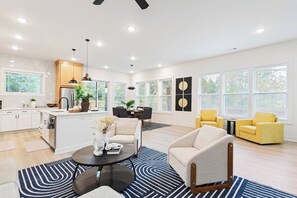 A modern kitchen with a central island, dining area with chairs, and a living room with a sofa and armchairs. - Sleek Designer Retreat Near Downtown Atlanta (Atlanta)