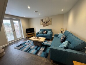 A modern living room with a sofa set, a coffee table, and a flat-screen TV. - 2 Bed cosy cottage close to Torksey golf club. (Lincoln)
