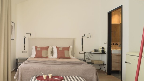 Una habitación de hotel moderna con una cama grande, mesitas de noche, un escritorio y un armario.