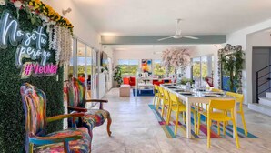 A modern interior with a dining area, colorful chairs, and a neon sign.