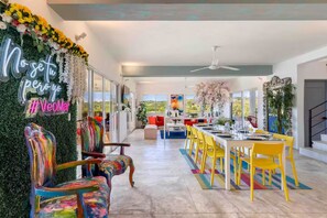 Ein modernes Interieur mit Essbereich, bunten Stühlen und einer Neonreklame.
