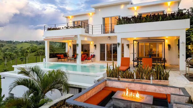 A modern house with a swimming pool, outdoor seating, and a fire pit.