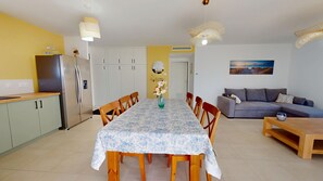 Ein Essbereich mit Tisch und Stühlen, einer Couch, einer Küche mit Schränken und einem Kühlschrank.